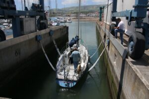 Traveller lowering the rigged sailboat into the water after a winter dry-dock.