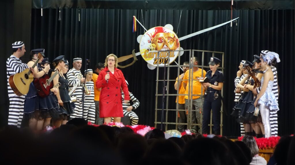Performers on stage in 2019 in Porto Martins Carnaval. Singing and dancing by community members dressed as police and a prisoner.