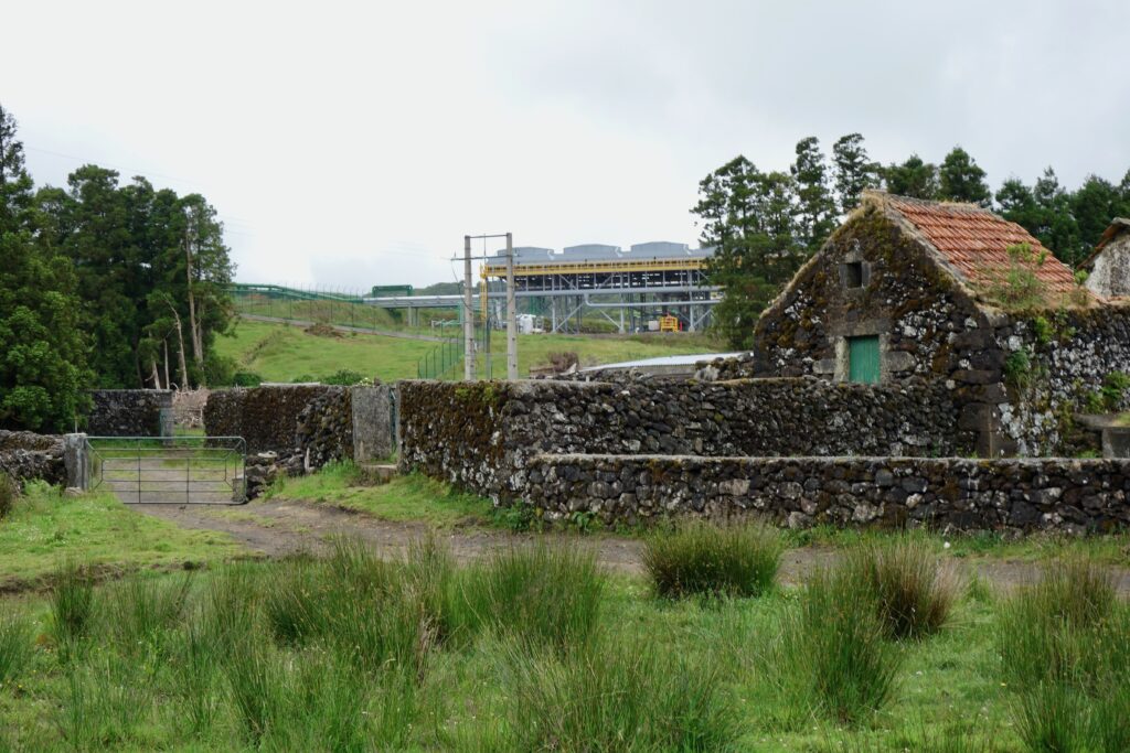 Ancient stone house and and nearby geothermal station on the interior of the island of Terceira.